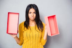 unhappy-woman-holding-empty-gift-box-over-gray-background-looking-camera-56773753.jpg